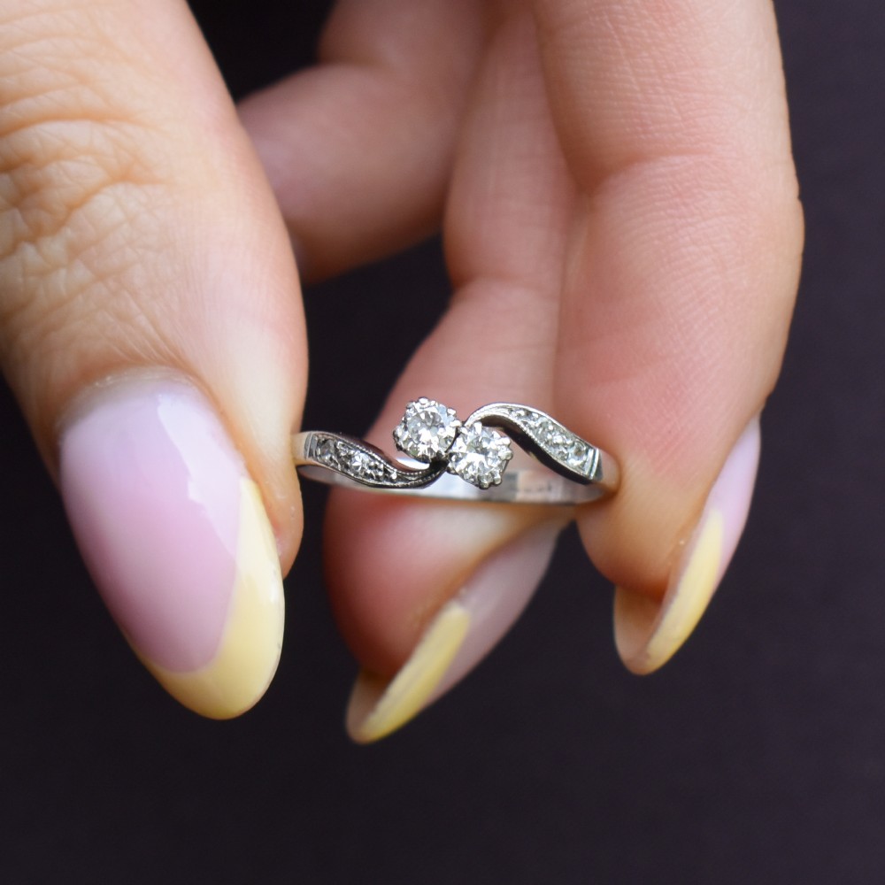 An antique 18ct white gold Toi et Moi ring featuring two central round diamonds set in a diagonal twist arrangement with diamond-set shoulders. View VIII