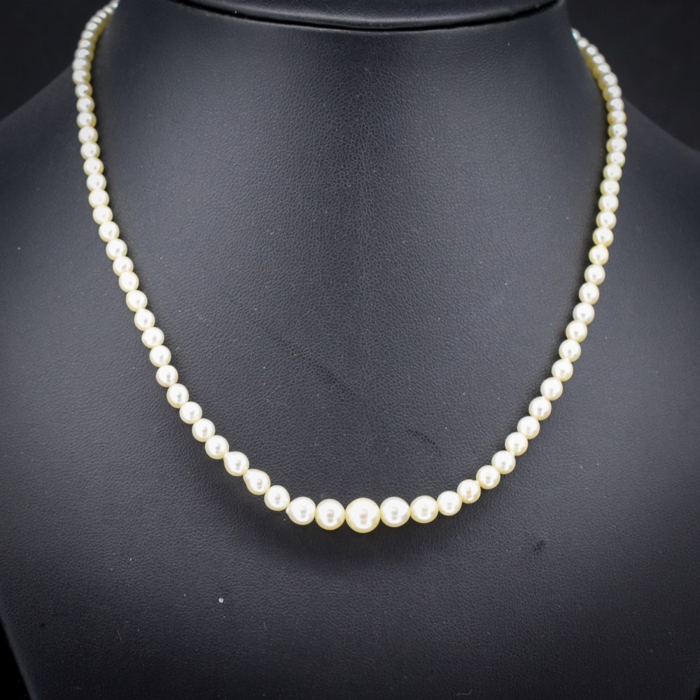 A 16-inch single strand necklace of graduated cream pearls fitted with a gold clasp.
