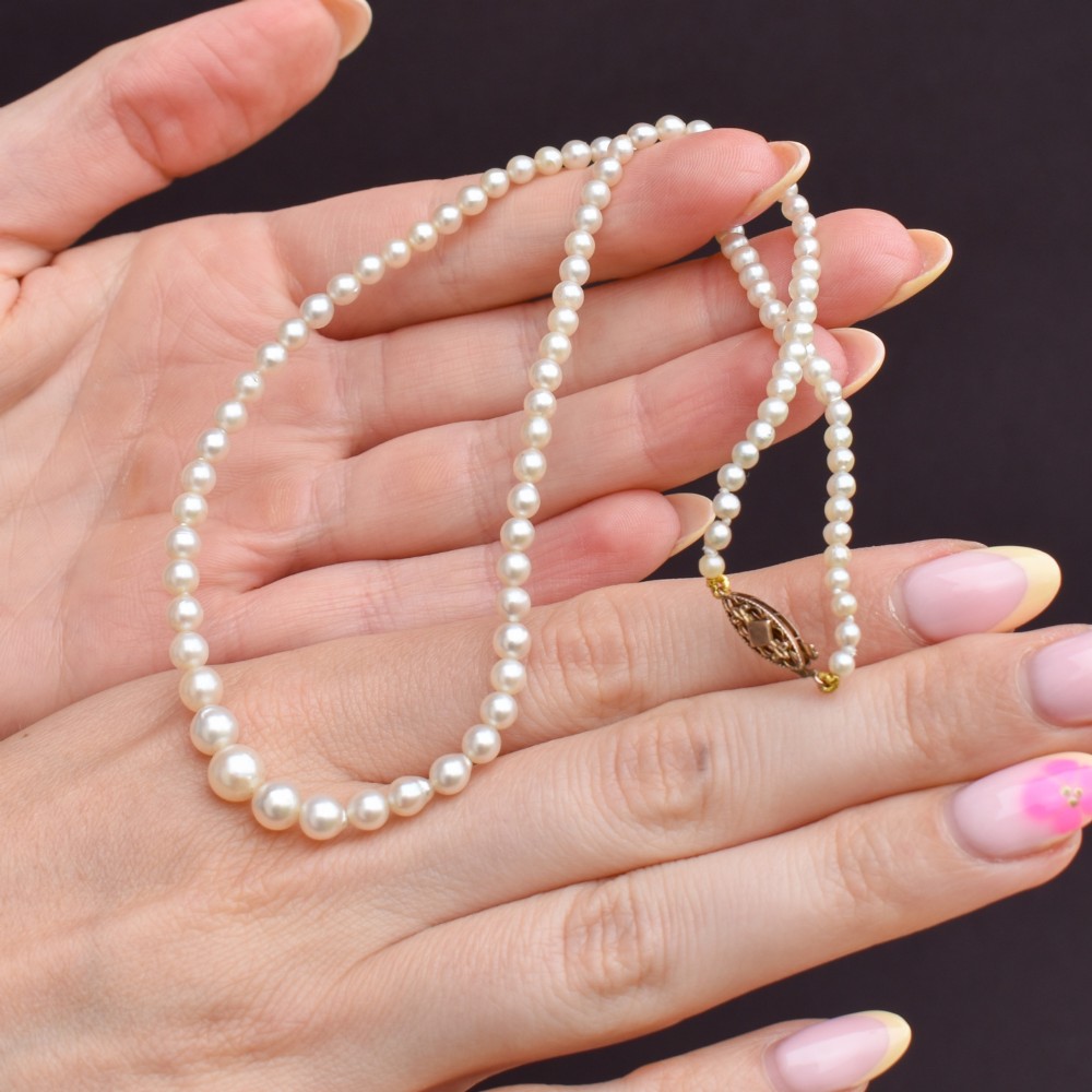 A 16-inch single strand necklace of graduated cream pearls fitted with a gold clasp. View VI