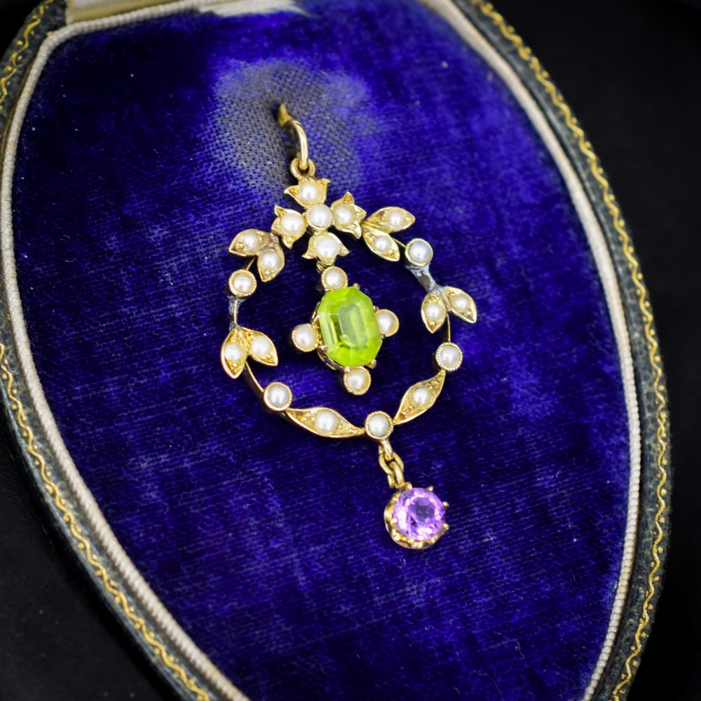 An Edwardian 15ct gold openwork lavalier pendant set with seed pearls, featuring an oval green peridot central stone and a suspended round purple amethyst drop. View II