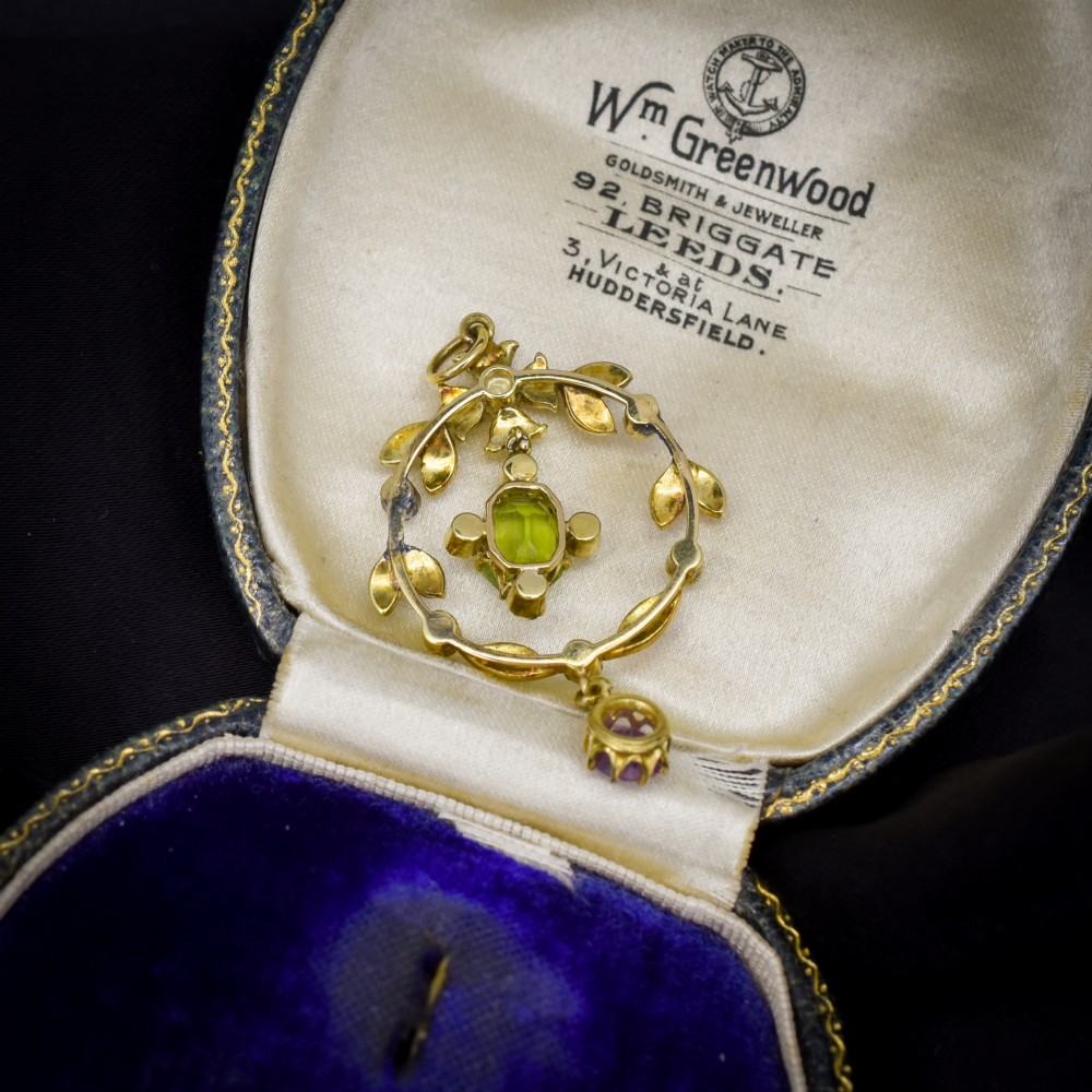 An Edwardian 15ct gold openwork lavalier pendant set with seed pearls, featuring an oval green peridot central stone and a suspended round purple amethyst drop. View III