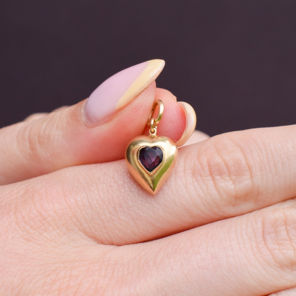 An antique yellow gold puffy heart-shaped charm featuring a central heart-cut purple amethyst paste gem. View VII