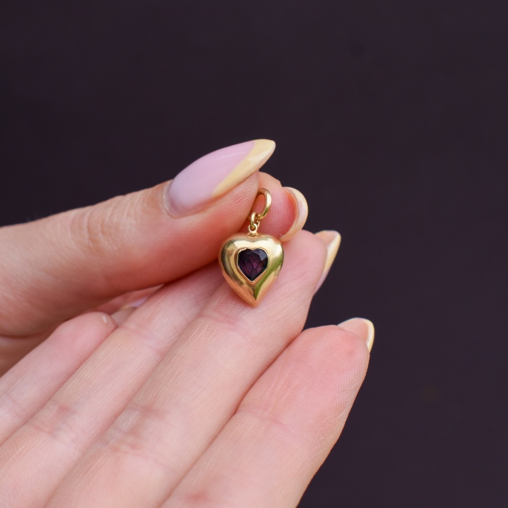 An antique yellow gold puffy heart-shaped charm featuring a central heart-cut purple amethyst paste gem. View VIII