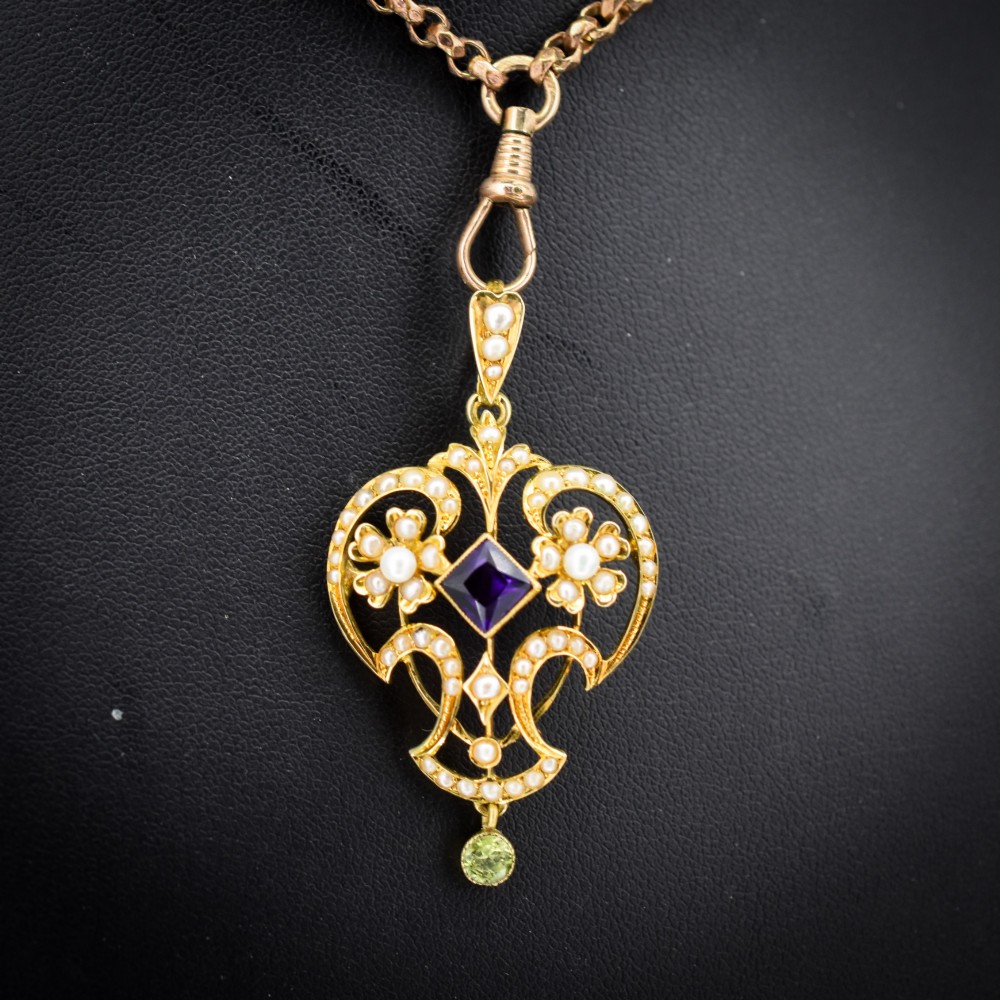 An ornate openwork 15ct gold Edwardian pendant decorated with seed pearls, a square central amethyst, and a hanging round peridot drop. View II