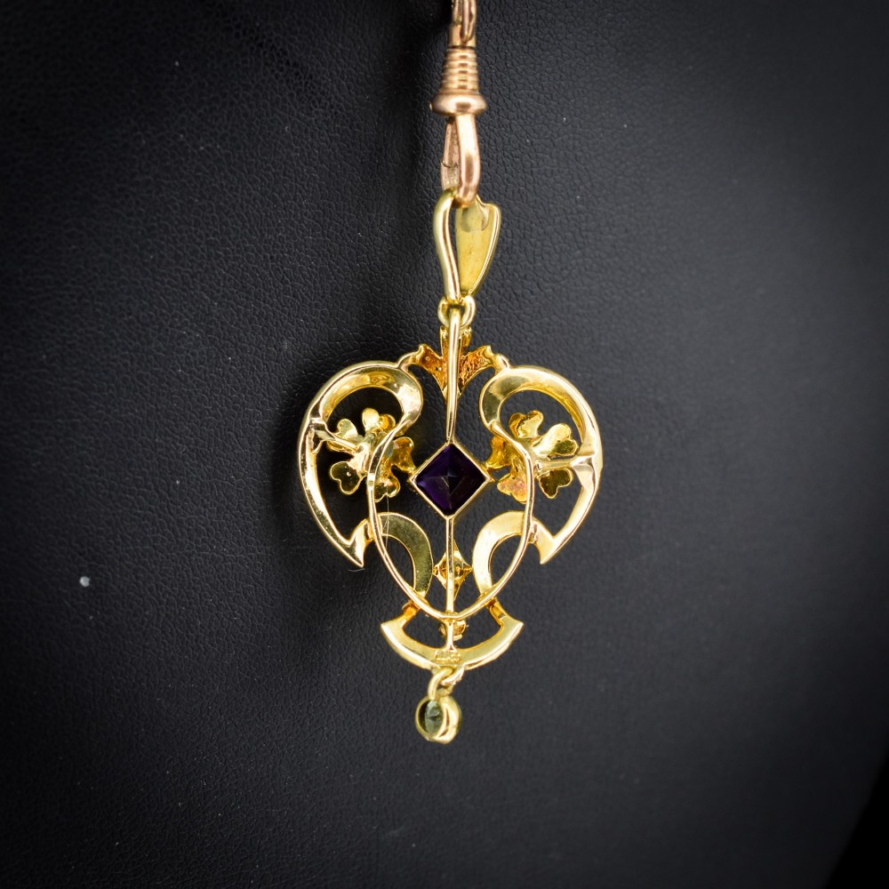 An ornate openwork 15ct gold Edwardian pendant decorated with seed pearls, a square central amethyst, and a hanging round peridot drop. View IV