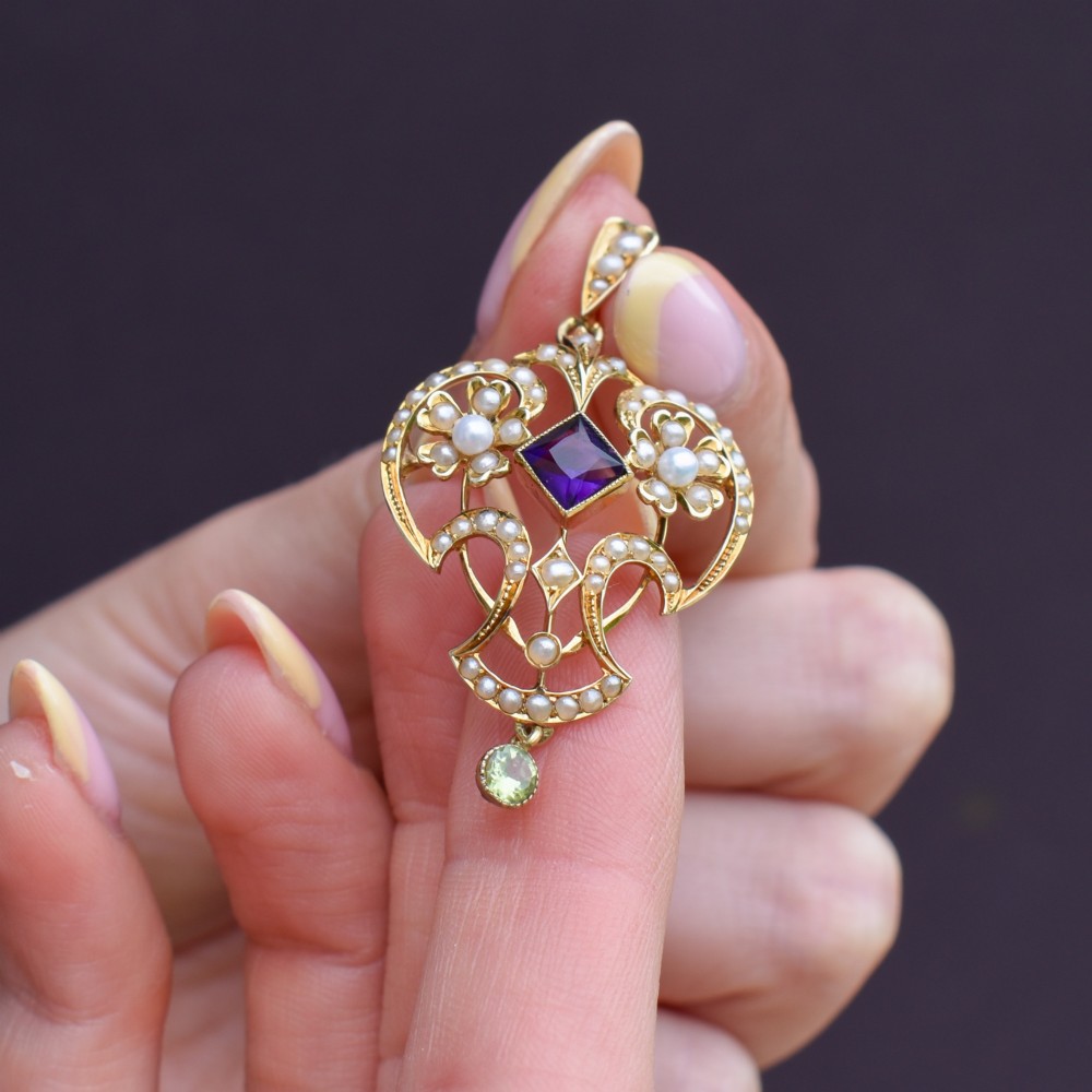 An ornate openwork 15ct gold Edwardian pendant decorated with seed pearls, a square central amethyst, and a hanging round peridot drop. View VII