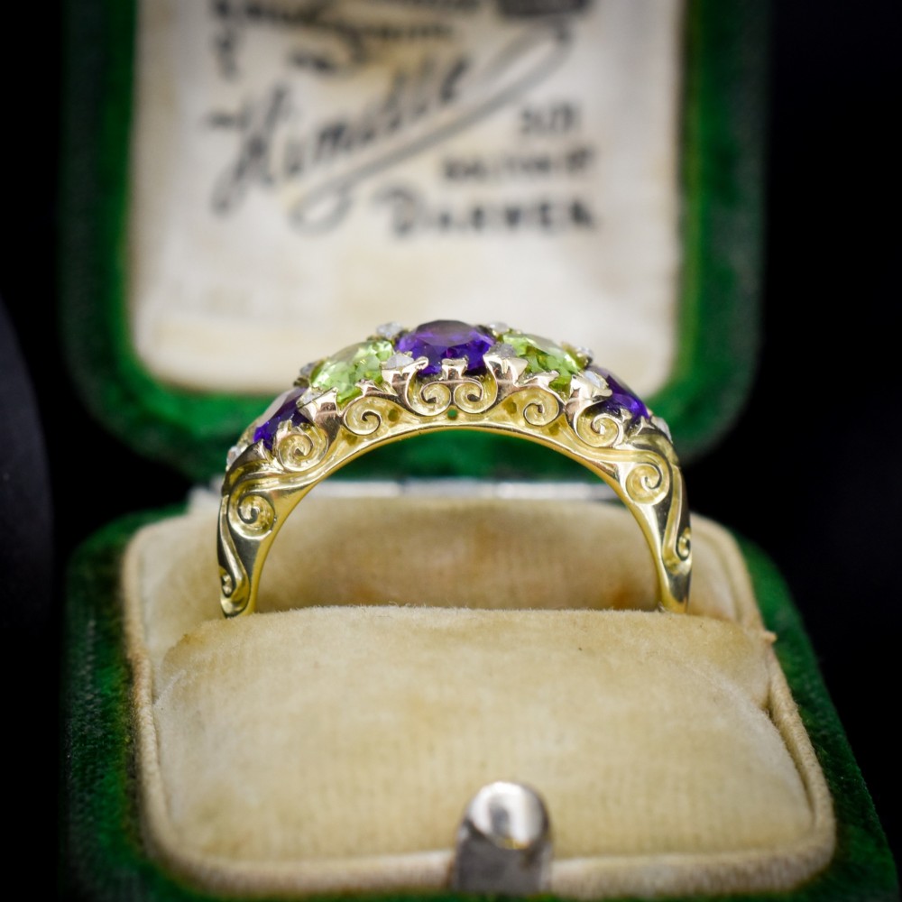 An antique 18ct yellow gold five-stone ring featuring alternating oval amethysts and peridots set with small diamond accents in a carved gallery. View II