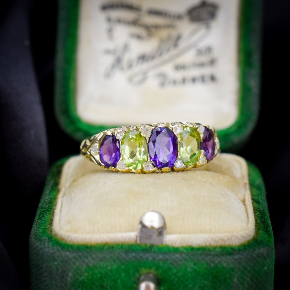 An antique 18ct yellow gold five-stone ring featuring alternating oval amethysts and peridots set with small diamond accents in a carved gallery. View III