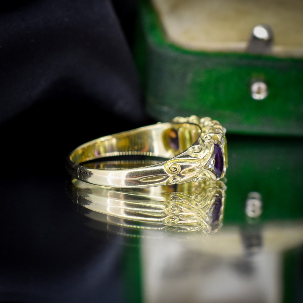 An antique 18ct yellow gold five-stone ring featuring alternating oval amethysts and peridots set with small diamond accents in a carved gallery. View V