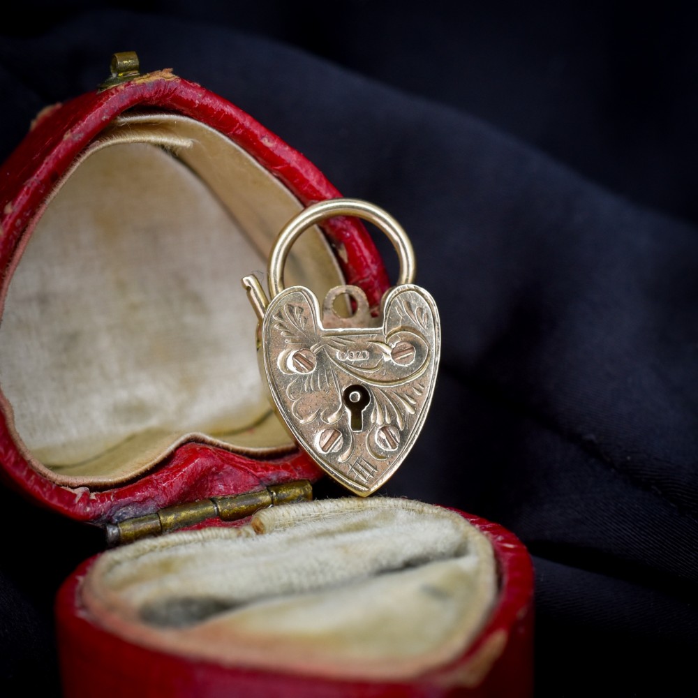 A 9ct yellow gold heart-shaped padlock charm featuring hand-engraved scrollwork and a keyhole detail.