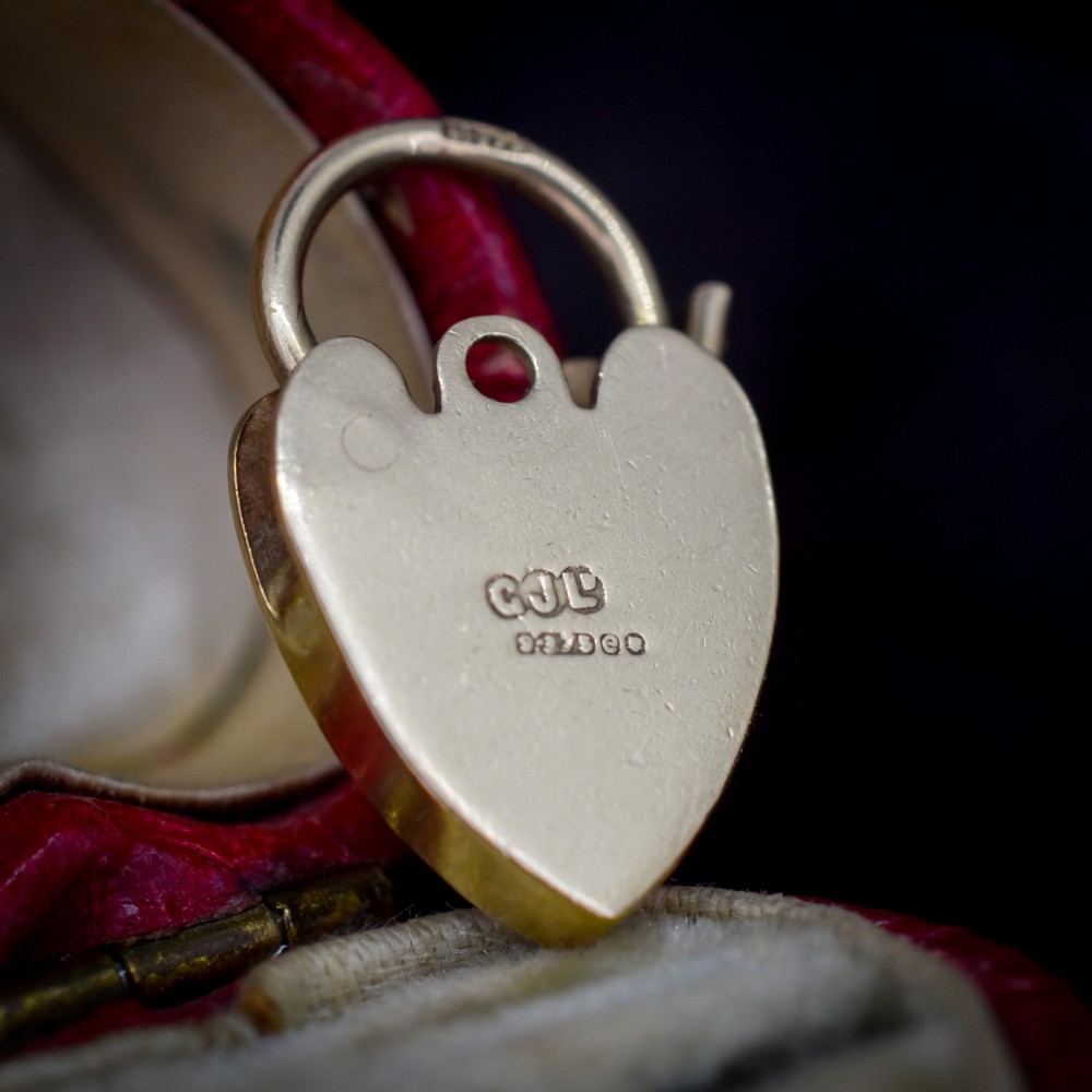 A 9ct yellow gold heart-shaped padlock charm featuring hand-engraved scrollwork and a keyhole detail. View IV