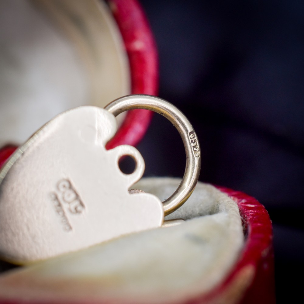 A 9ct yellow gold heart-shaped padlock charm featuring hand-engraved scrollwork and a keyhole detail. View V