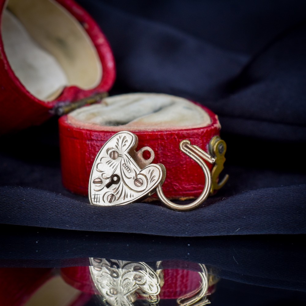 A 9ct yellow gold heart-shaped padlock charm featuring hand-engraved scrollwork and a keyhole detail. View VI