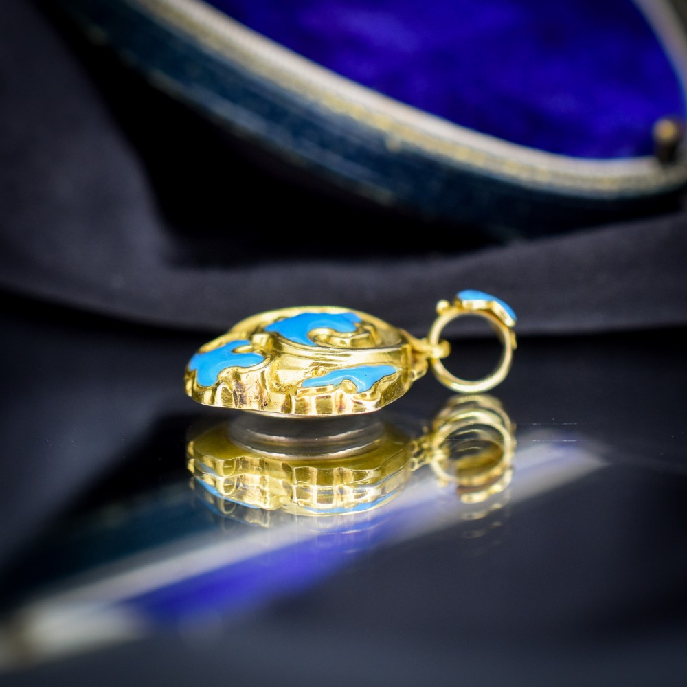 An antique 18ct yellow gold pendant featuring swirling scrollwork inlaid with vibrant turquoise blue enamel. View IV