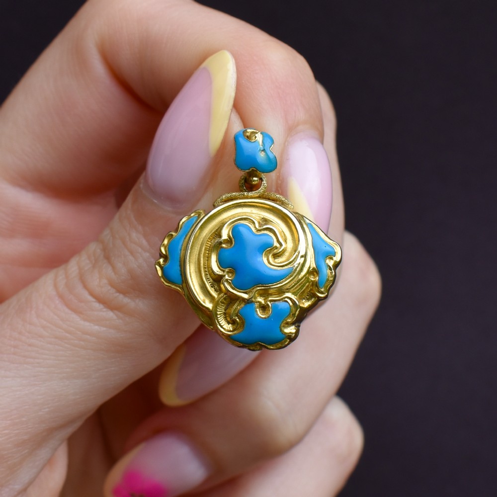 An antique 18ct yellow gold pendant featuring swirling scrollwork inlaid with vibrant turquoise blue enamel. View V