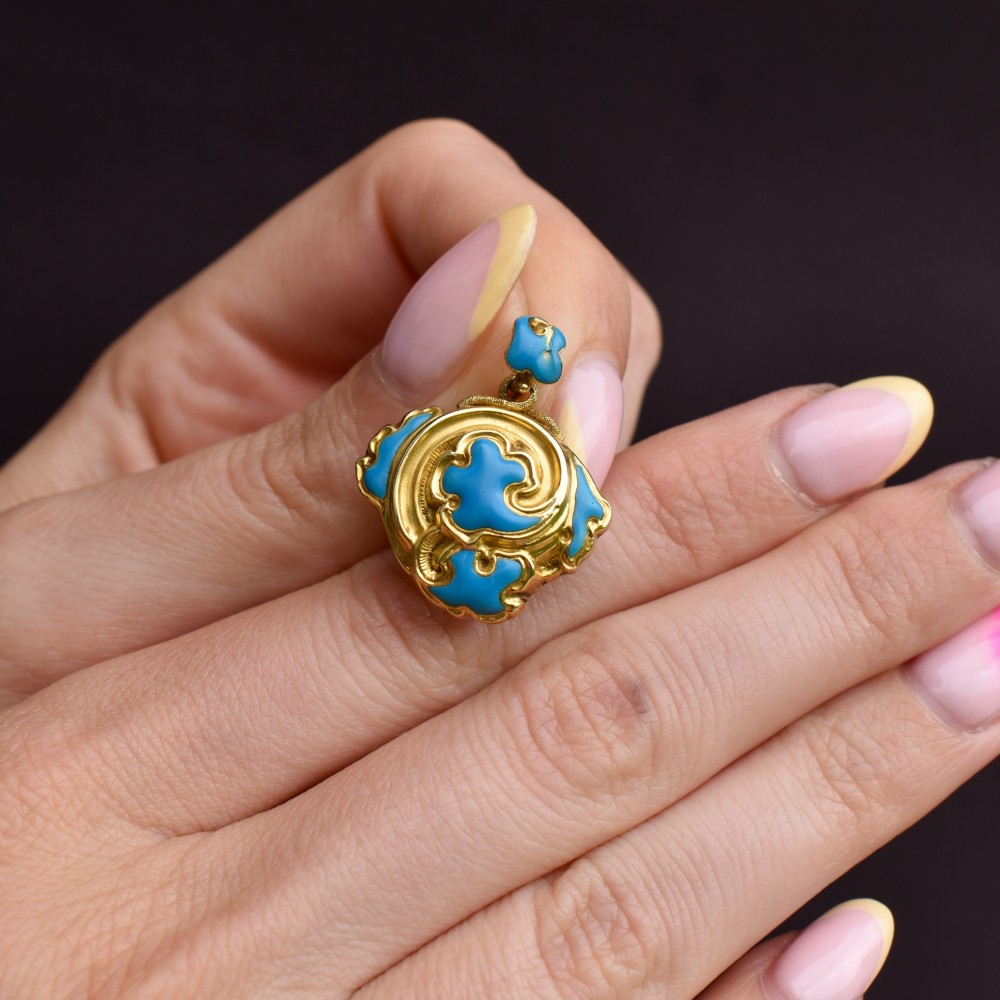 An antique 18ct yellow gold pendant featuring swirling scrollwork inlaid with vibrant turquoise blue enamel. View VI