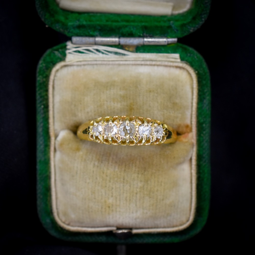 An 18ct yellow gold five-stone ring set with old cut diamonds in a carved scrollwork gallery.