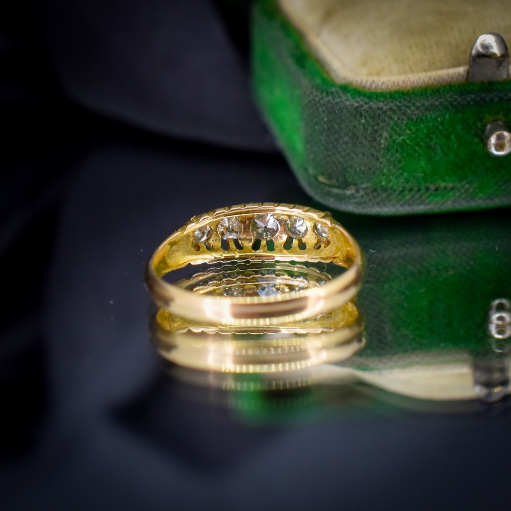 An 18ct yellow gold five-stone ring set with old cut diamonds in a carved scrollwork gallery. View IV
