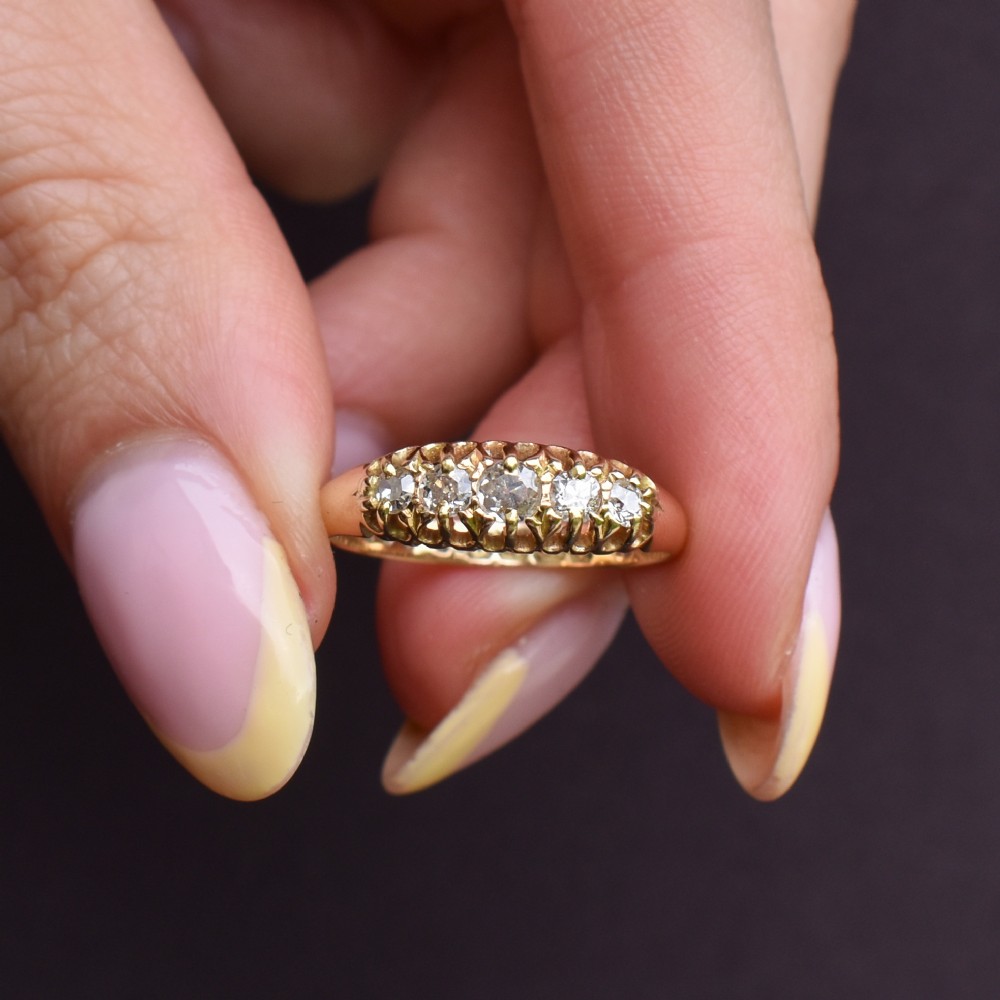 An 18ct yellow gold five-stone ring set with old cut diamonds in a carved scrollwork gallery. View VI