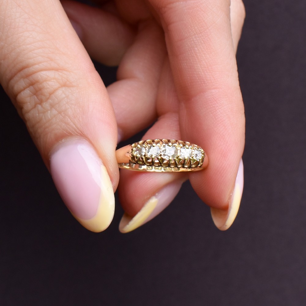 An 18ct yellow gold five-stone ring set with old cut diamonds in a carved scrollwork gallery. View VII