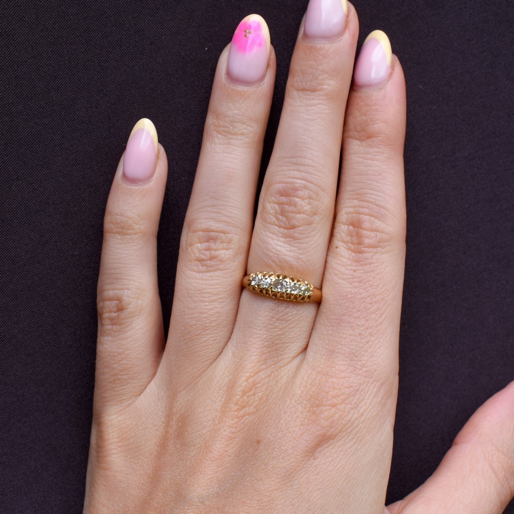 An 18ct yellow gold five-stone ring set with old cut diamonds in a carved scrollwork gallery. View VIII