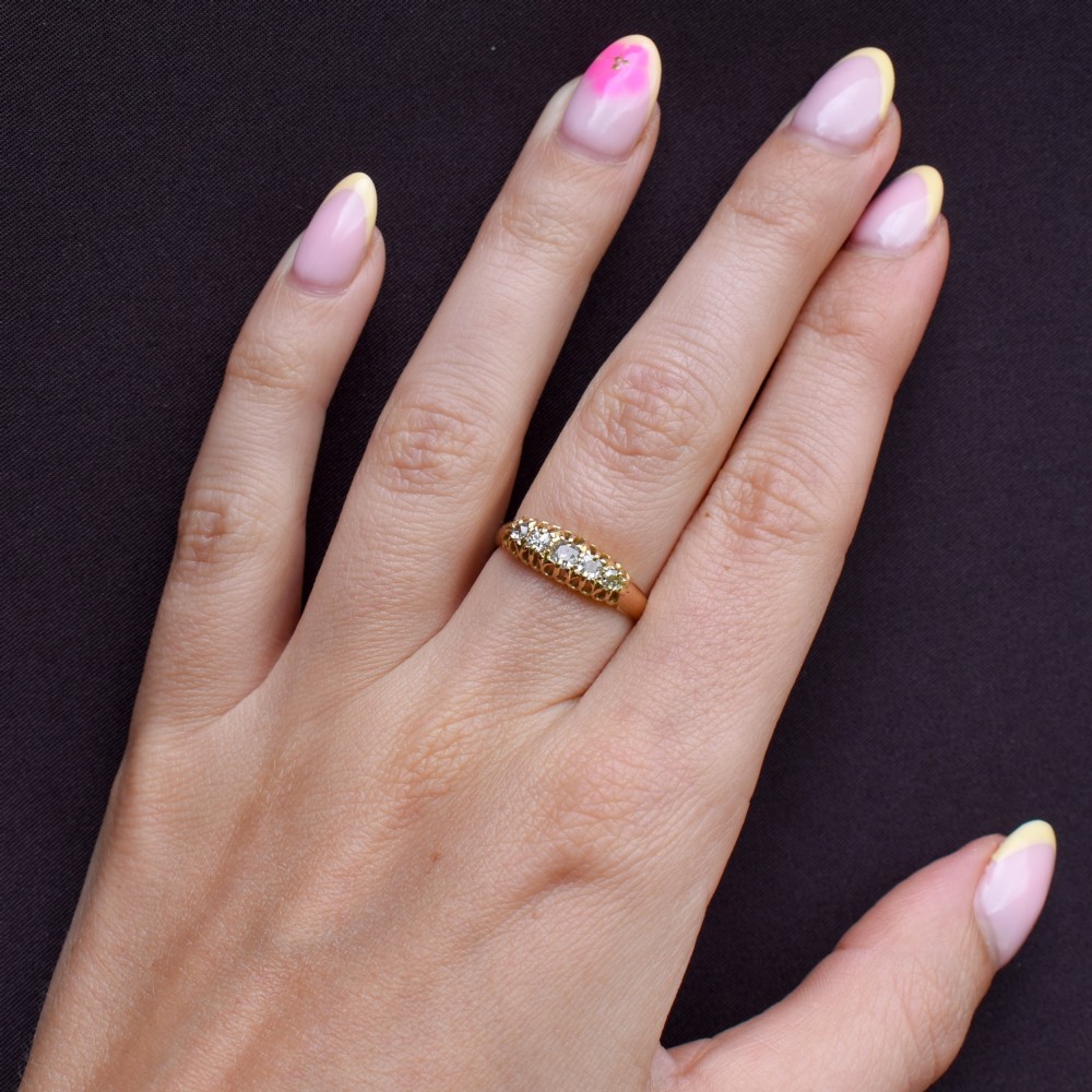 An 18ct yellow gold five-stone ring set with old cut diamonds in a carved scrollwork gallery. View IX