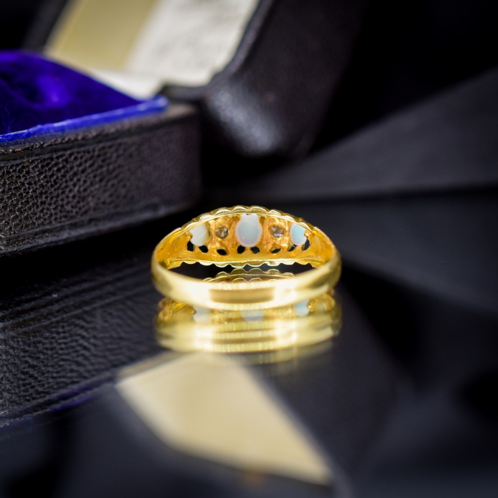 An Edwardian 18ct yellow gold boat ring set with three cabochon natural opals and two small diamonds within a carved scrollwork gallery. View III