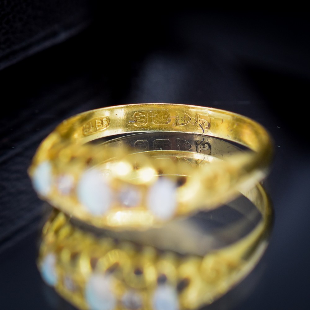An Edwardian 18ct yellow gold boat ring set with three cabochon natural opals and two small diamonds within a carved scrollwork gallery. View V