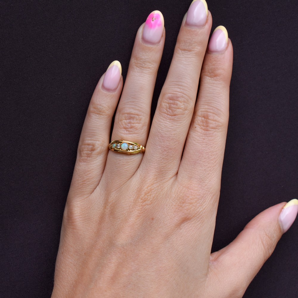 An Edwardian 18ct yellow gold boat ring set with three cabochon natural opals and two small diamonds within a carved scrollwork gallery. View VIII