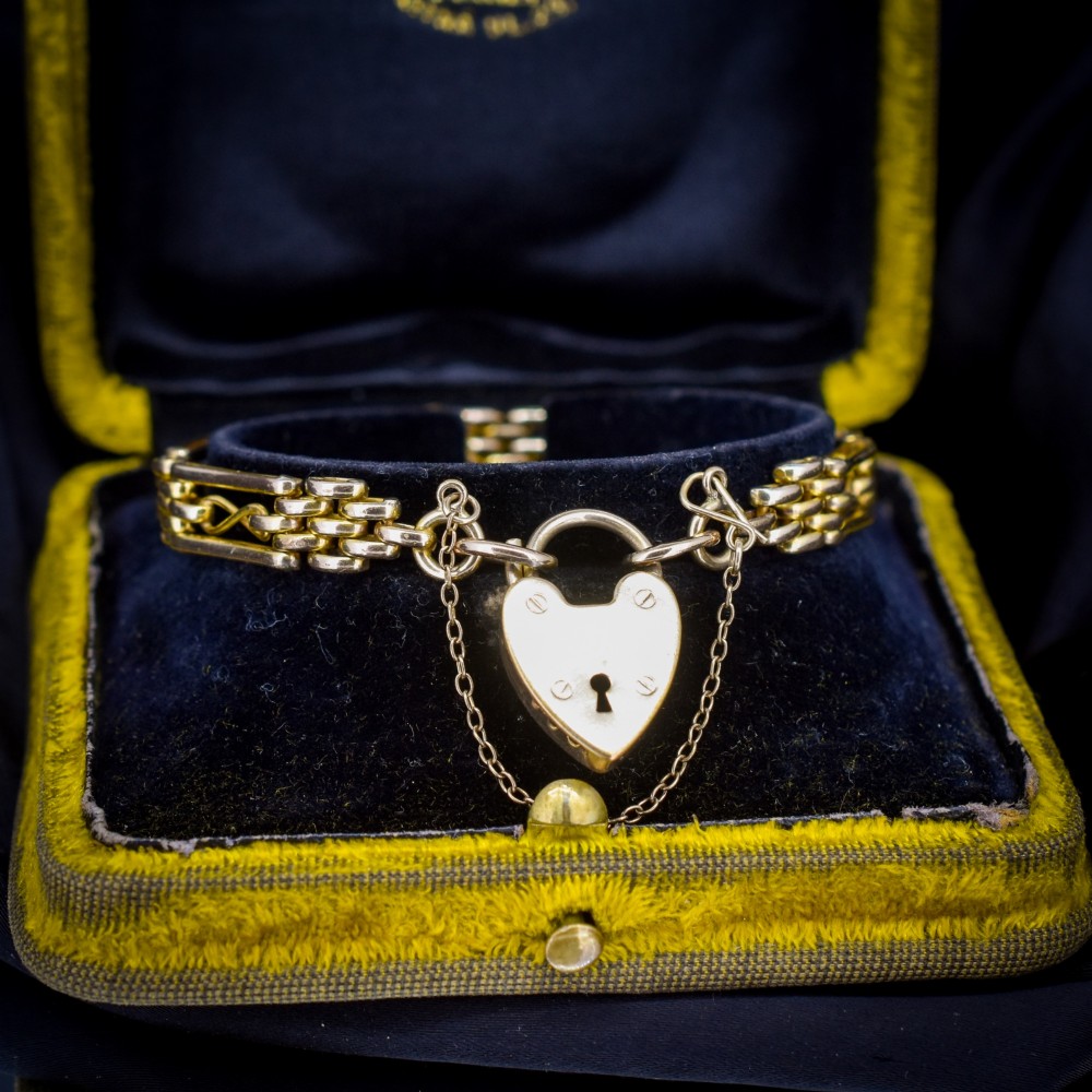 An antique rolled gold gate link bracelet featuring multi-row interlocking bars and a central heart-shaped padlock clasp with a safety chain. View III