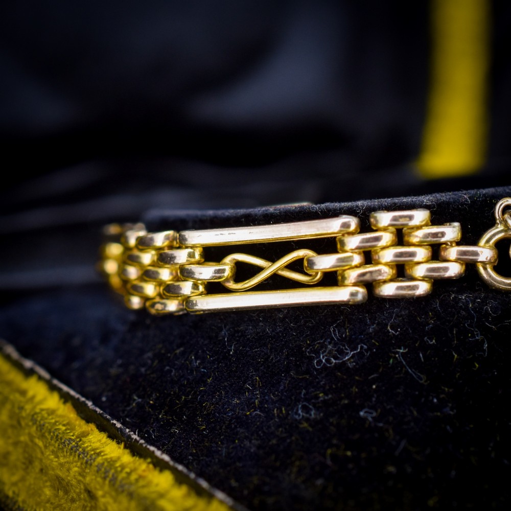 An antique rolled gold gate link bracelet featuring multi-row interlocking bars and a central heart-shaped padlock clasp with a safety chain. View V