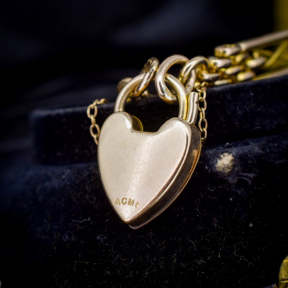 An antique rolled gold gate link bracelet featuring multi-row interlocking bars and a central heart-shaped padlock clasp with a safety chain. View VI