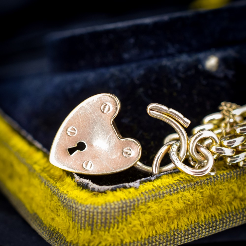 An antique rolled gold gate link bracelet featuring multi-row interlocking bars and a central heart-shaped padlock clasp with a safety chain. View VII