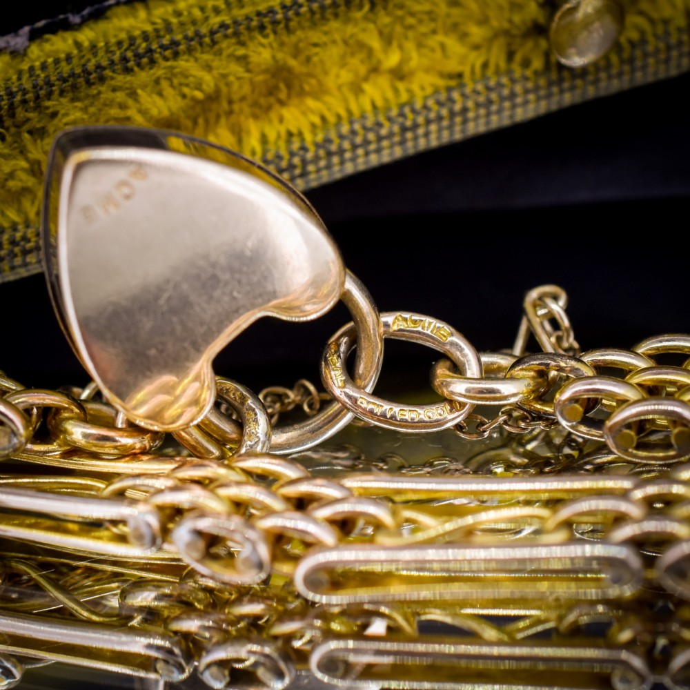 An antique rolled gold gate link bracelet featuring multi-row interlocking bars and a central heart-shaped padlock clasp with a safety chain. View VIII