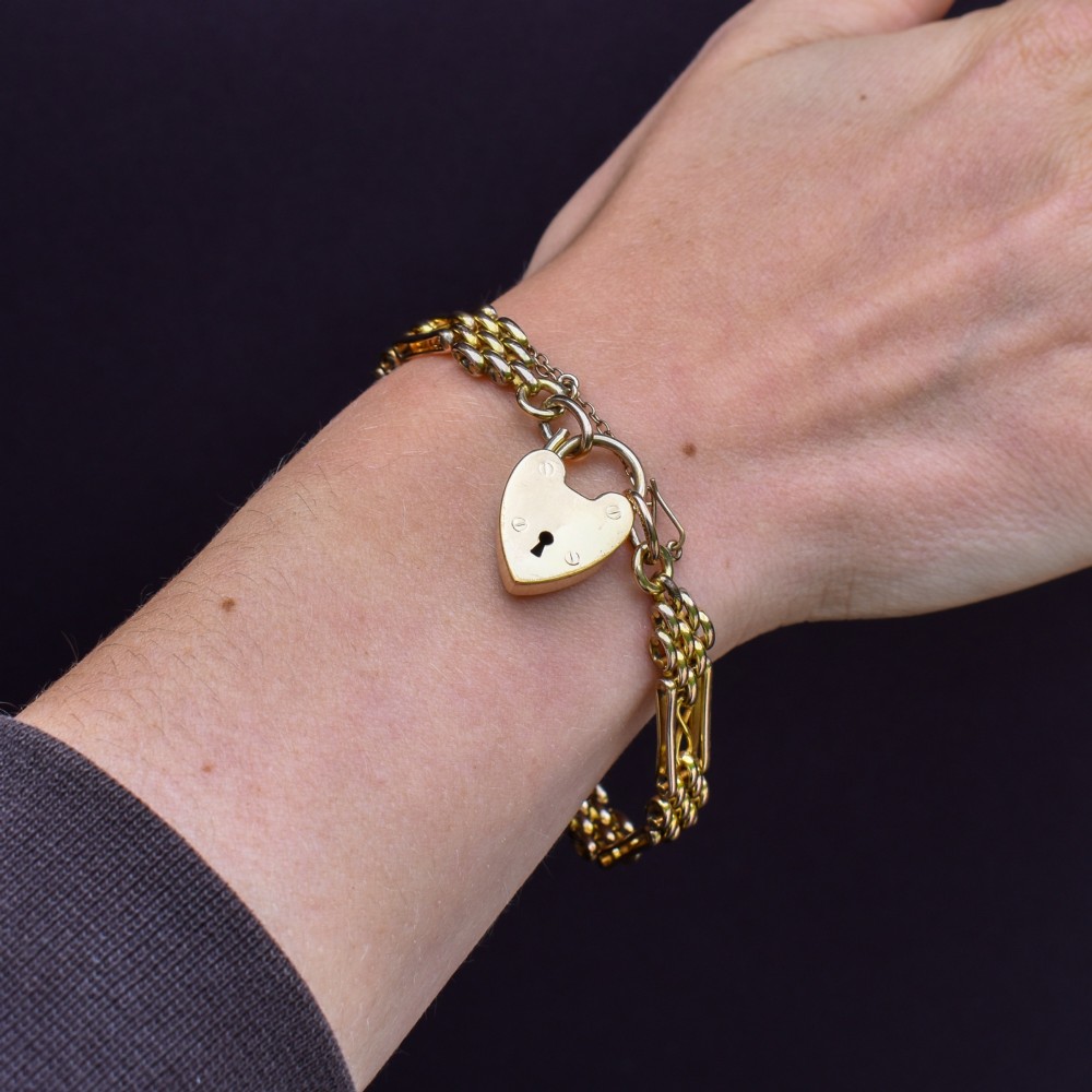 An antique rolled gold gate link bracelet featuring multi-row interlocking bars and a central heart-shaped padlock clasp with a safety chain. View XI
