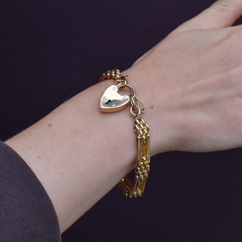 An antique rolled gold gate link bracelet featuring multi-row interlocking bars and a central heart-shaped padlock clasp with a safety chain. View XII