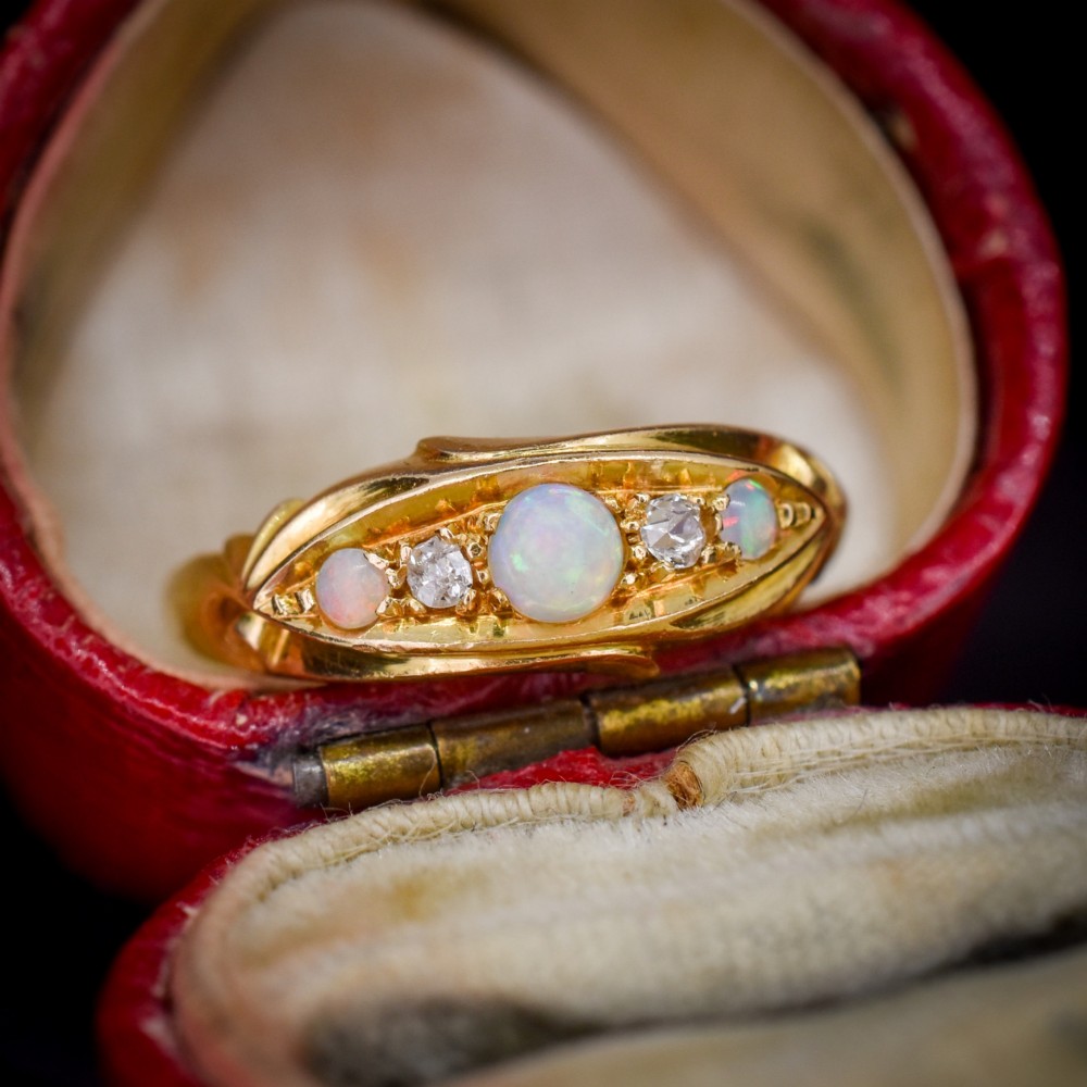 An antique 18ct yellow gold boat setting ring featuring three cabochon opals and two small diamonds.