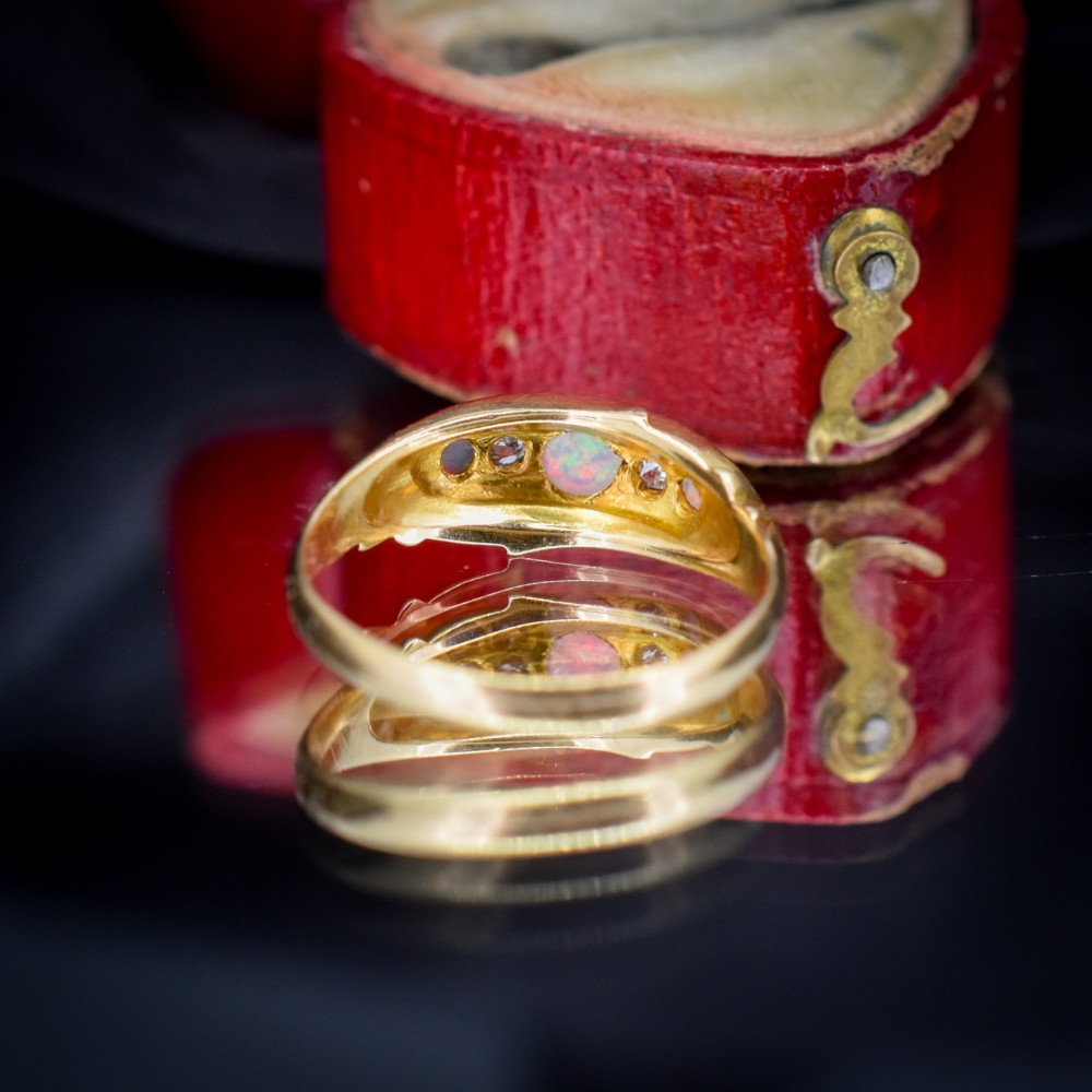 An antique 18ct yellow gold boat setting ring featuring three cabochon opals and two small diamonds. View V