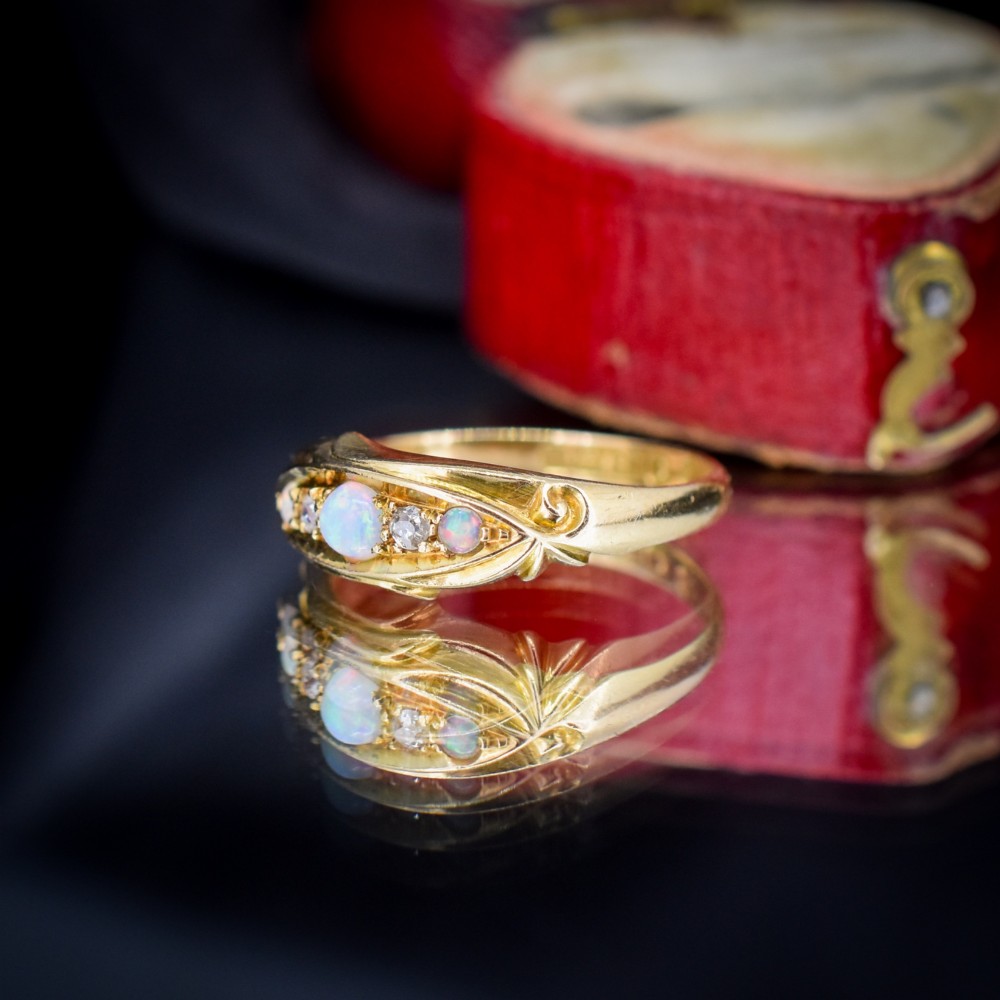An antique 18ct yellow gold boat setting ring featuring three cabochon opals and two small diamonds. View VI
