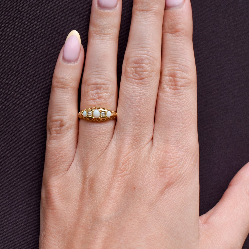 An antique 18ct yellow gold boat setting ring featuring three cabochon opals and two small diamonds. View X