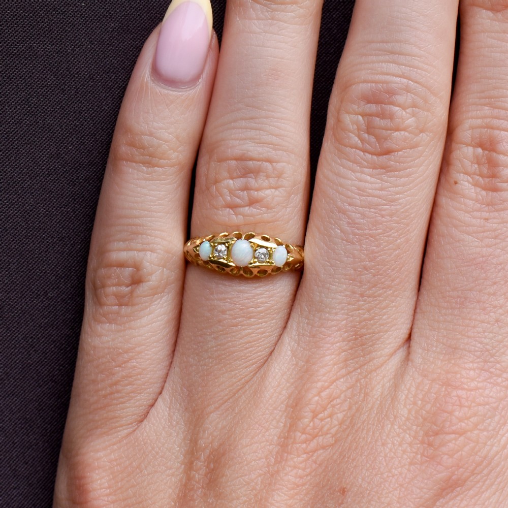 An antique 18ct yellow gold boat setting ring featuring three cabochon opals and two small diamonds. View XI