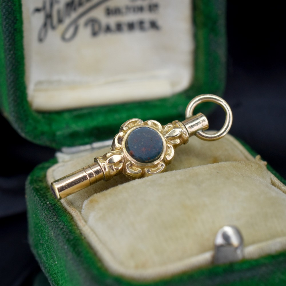 A gold-cased pocket watch key set with a central round dark green agate stone and fitted with a top suspension ring. View II
