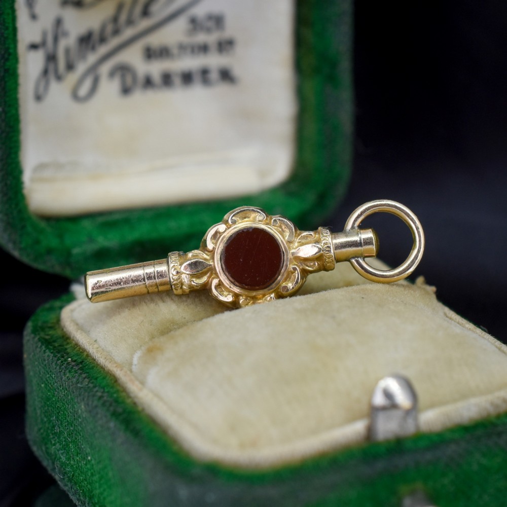 A gold-cased pocket watch key set with a central round dark green agate stone and fitted with a top suspension ring. View IV