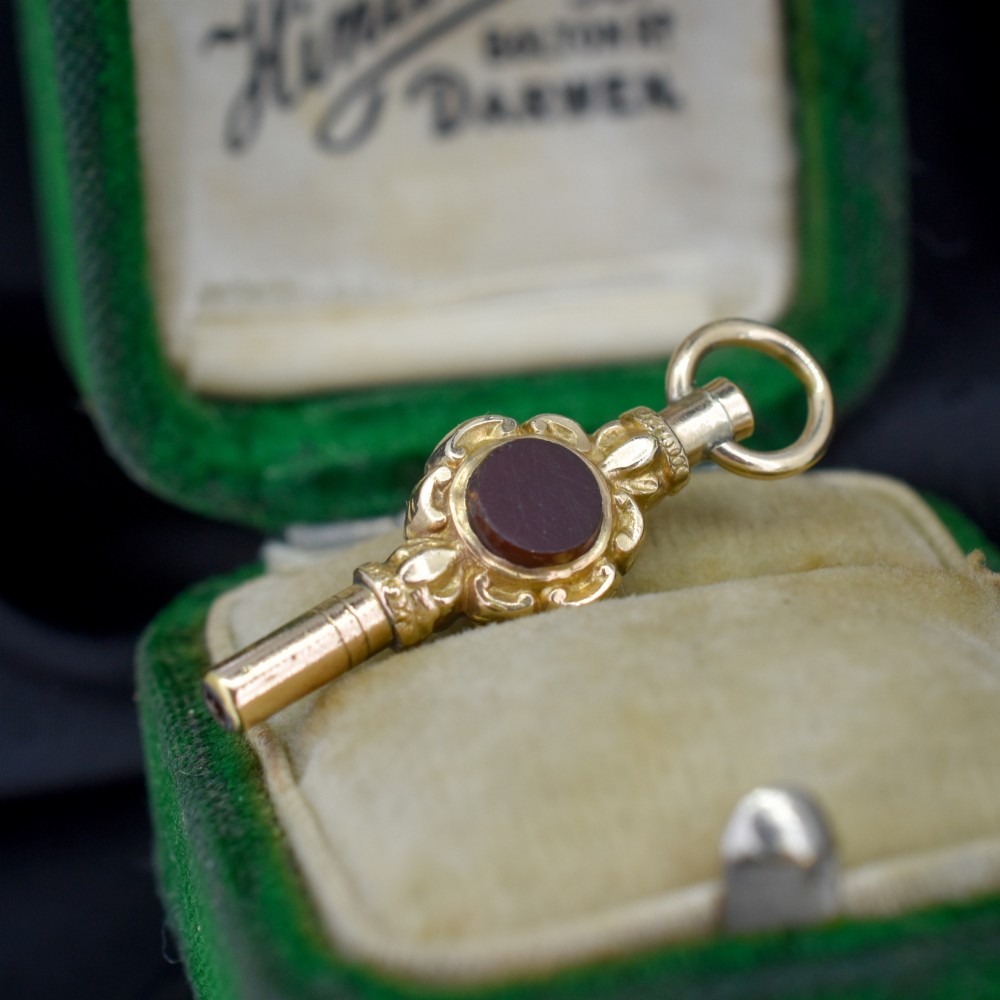 A gold-cased pocket watch key set with a central round dark green agate stone and fitted with a top suspension ring. View V