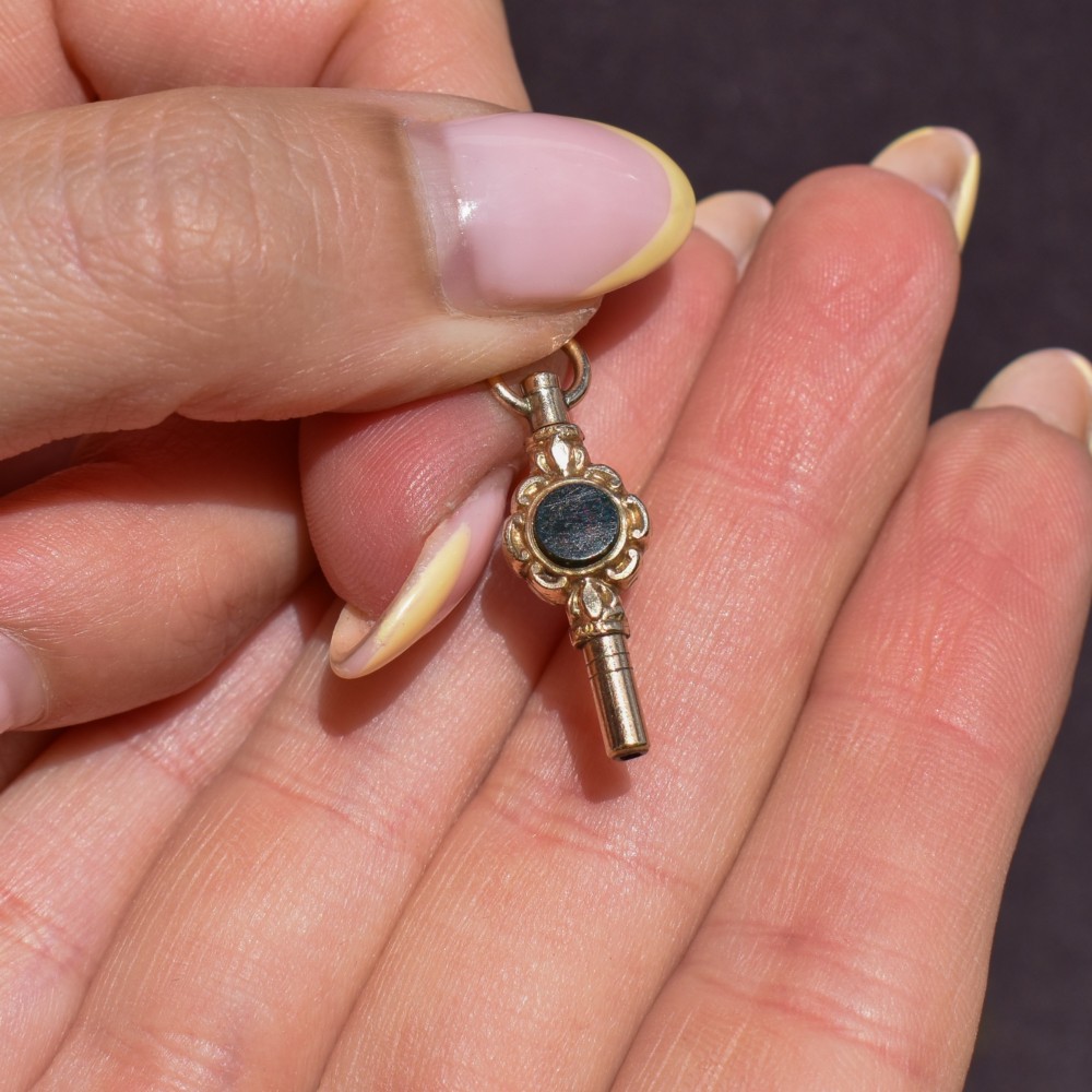 A gold-cased pocket watch key set with a central round dark green agate stone and fitted with a top suspension ring. View VI