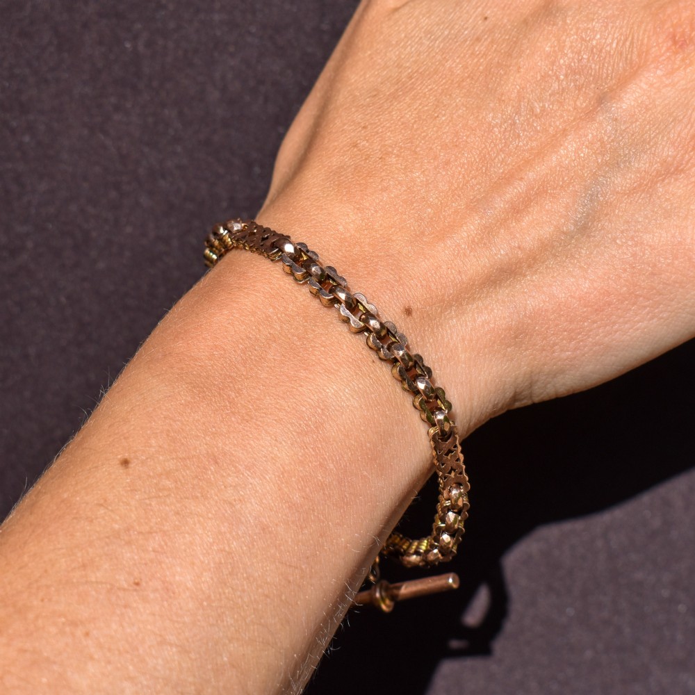 An antique 9ct yellow gold fancy link chain bracelet with a swivel clasp and suspended T-bar element. View VI