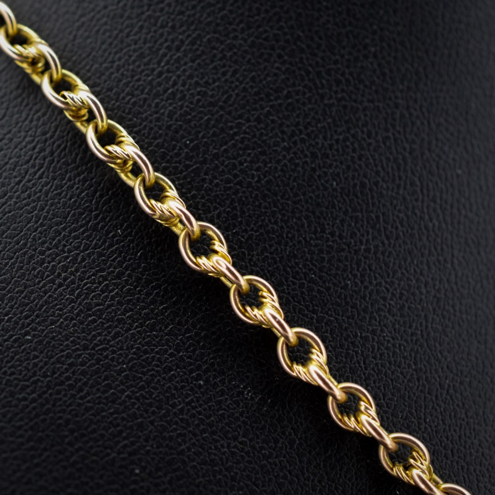 An antique 9ct gold double Albert watch chain featuring love knot links, two swivel clasps, and a central T-bar. View V