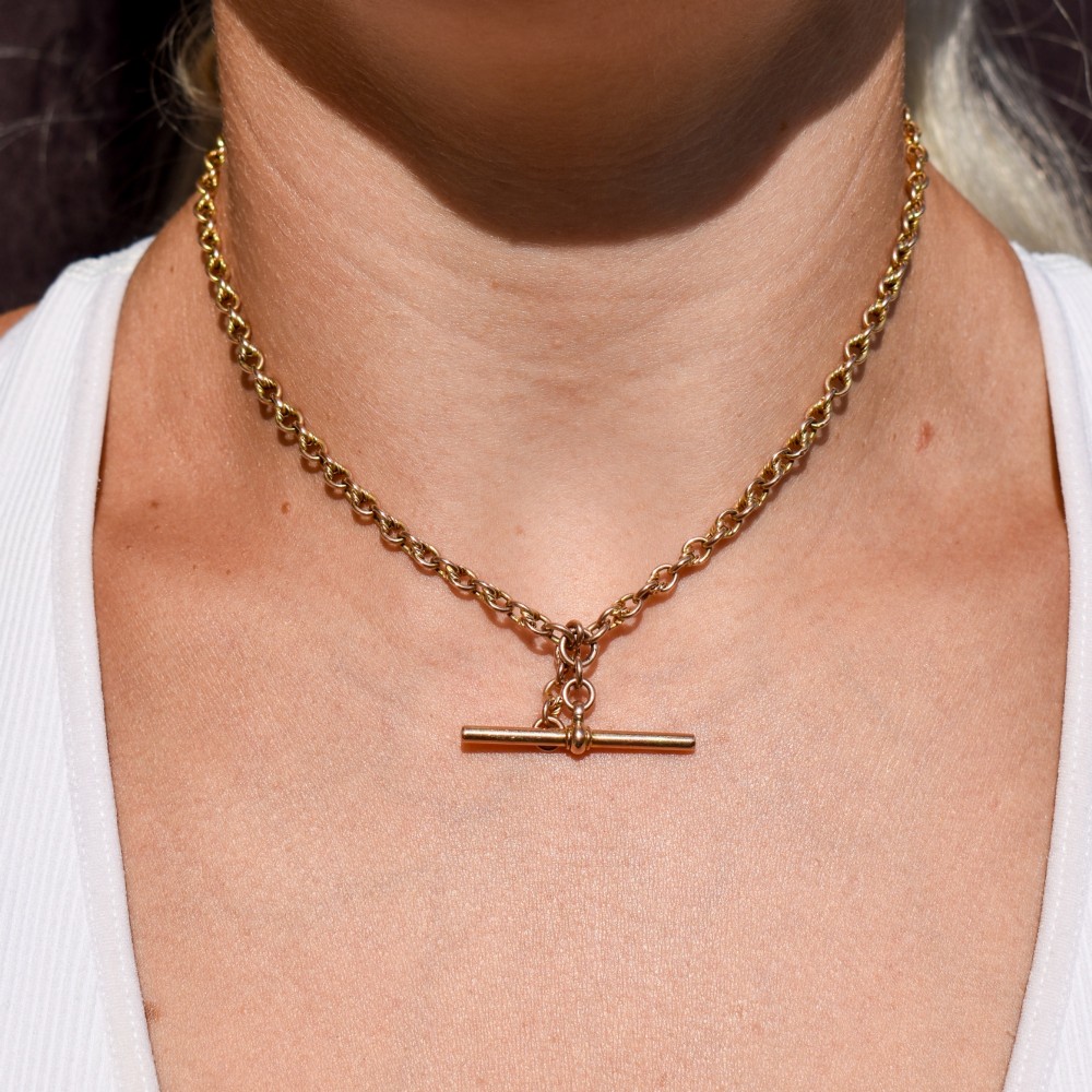 An antique 9ct gold double Albert watch chain featuring love knot links, two swivel clasps, and a central T-bar. View VIII