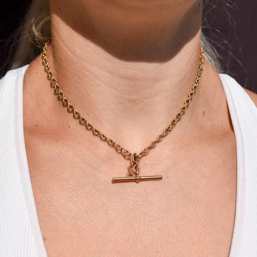 An antique 9ct gold double Albert watch chain featuring love knot links, two swivel clasps, and a central T-bar. View IX