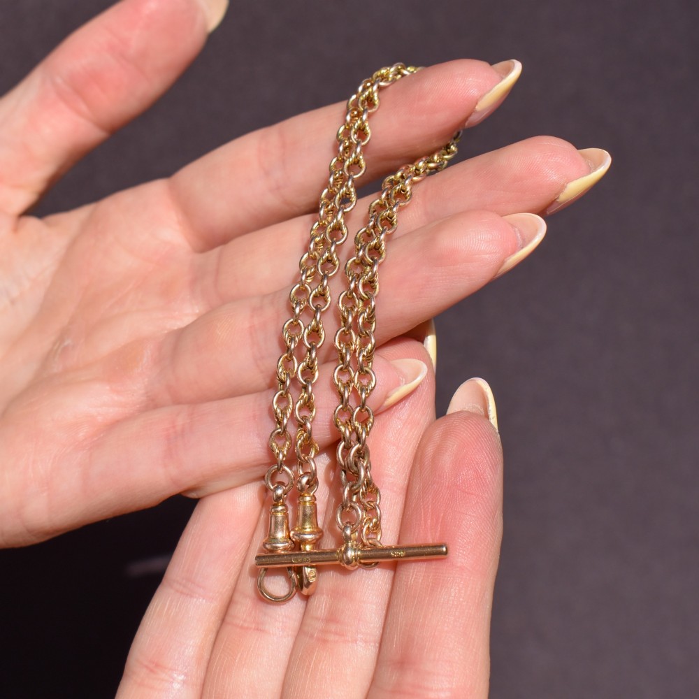 An antique 9ct gold double Albert watch chain featuring love knot links, two swivel clasps, and a central T-bar. View X